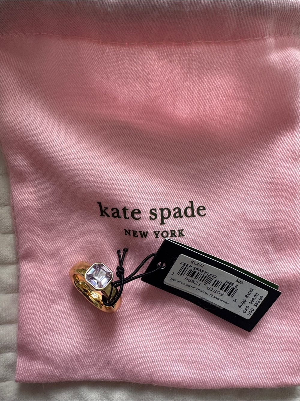 kate spade gold-tone ring with violet crystal on pink pouch